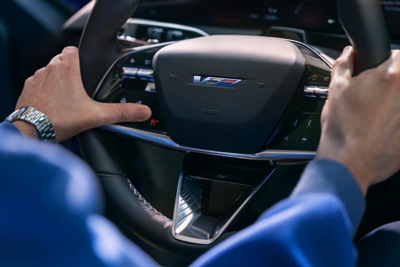 Close-up of a Man About to Press the V-Button on the 2026 OPTIQ-V Steering Wheel | Marion Chevrolet Buick GMC Cadillac in Marion IL